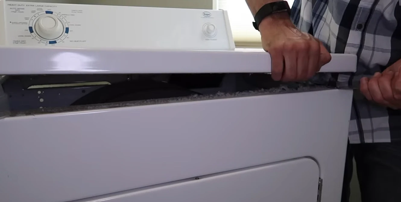 Dryer repair Plano technician lifting the top panel of a dryer to reach the parts inside