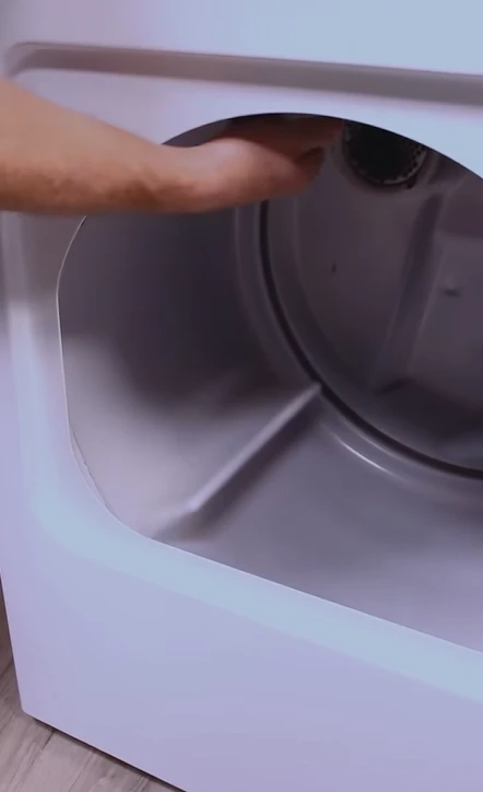 Hand reaching into the drum of a dryer