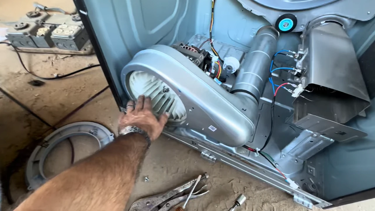 Hand on the blower housing and exhaust duct of an opened dryer