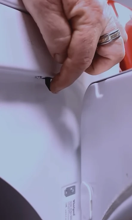 Checking the door latch area on the front of a dryer