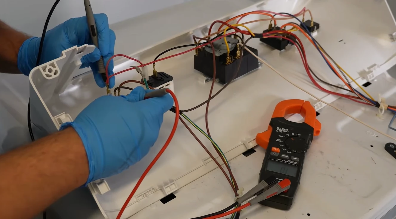 Technician testing dryer wiring with a clamp meter and probe