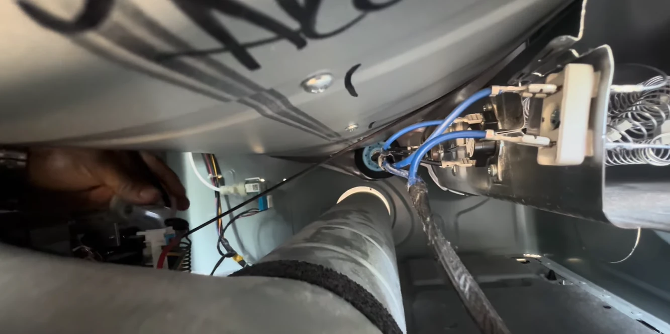 Close-up of the wiring and exhaust duct under the drum of an opened dryer