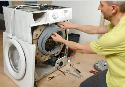 Two people repairing a front-load laundry appliance