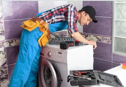 Technician working on the back of a laundry appliance with tools around