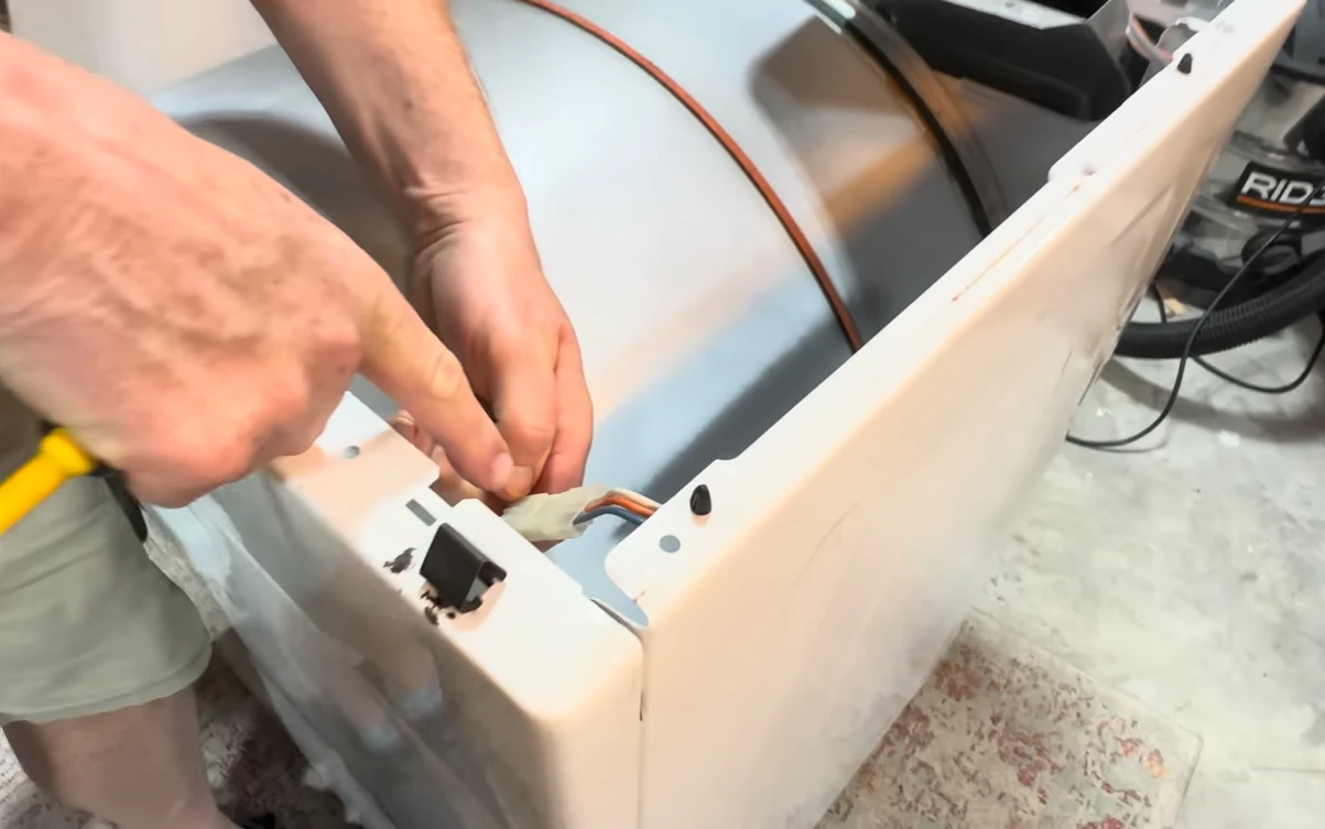 Technician removing the side panel of a white dryer